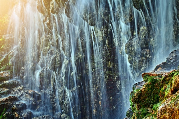 A large waterfall in a cave in the sun's rays