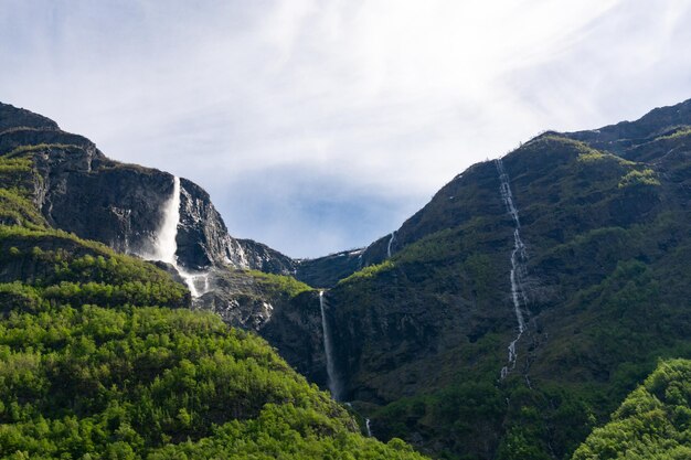 Large waterfall that rises in the mountains surrounded by green trees in Norway