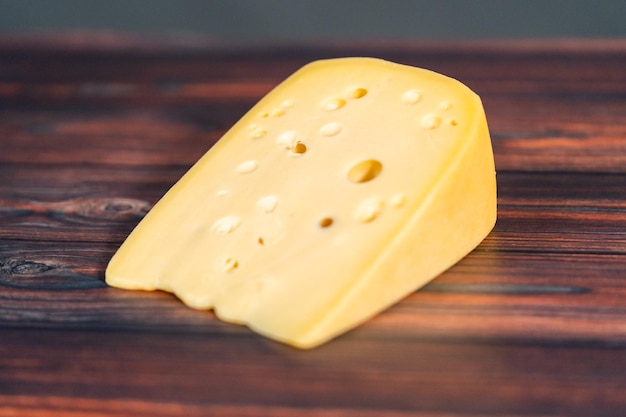 Large wedge of semi soft part-skim swiss cheese on a dark wooden background.