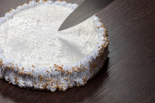 Large white cake with a clank top is cut with a knife