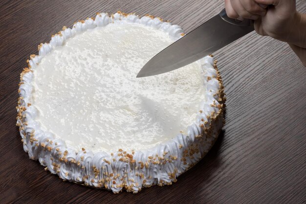 Large white cake with a clank top is cut with a knife