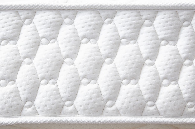 Large white mattress with stitched finishing lines. Close-up. Side view. Copy space.