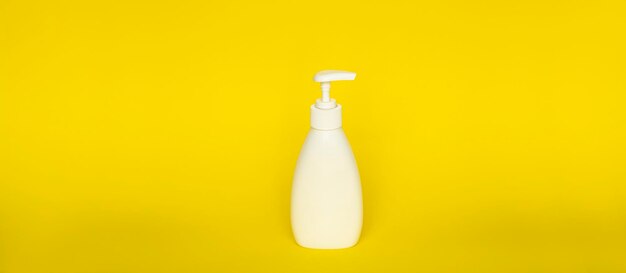 Large white plastic bottle with pump dispenser on yellow background mock up template for design