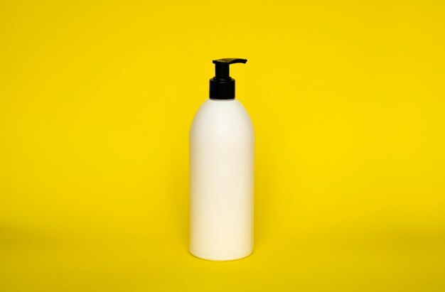 Large white plastic bottle with pump dispenser on yellow background mock up template for design