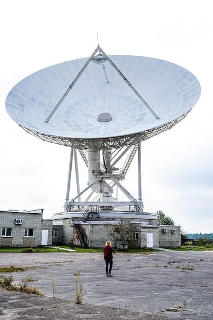 A large white satellite dish is in front of a building.