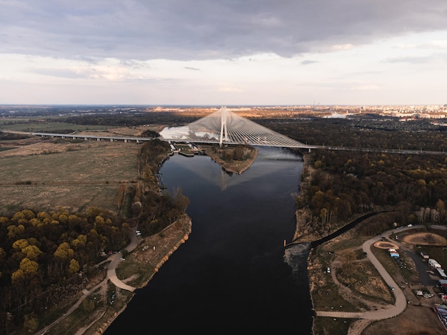 A large white suspension bridge over the river on which cars drive in Wroclaw Poland shot from a drone