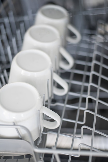 Photo large white tea mugs are stacked in the dishwasher close up