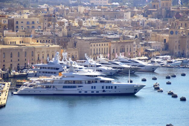 Photo a large white yacht is docked in a harbor with a lot of other boats.