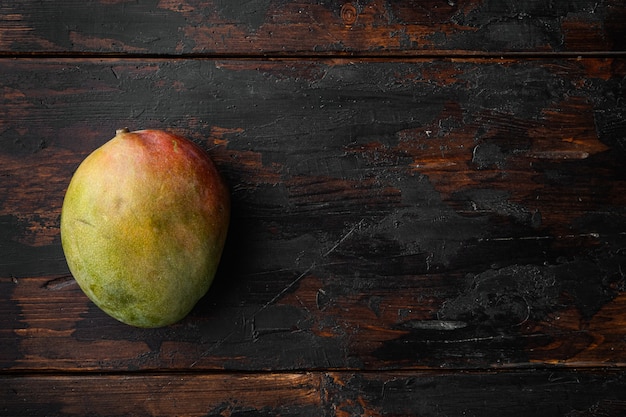 Large whole tasty Mango set, on old dark  wooden table background, top view flat lay, with copy space for text