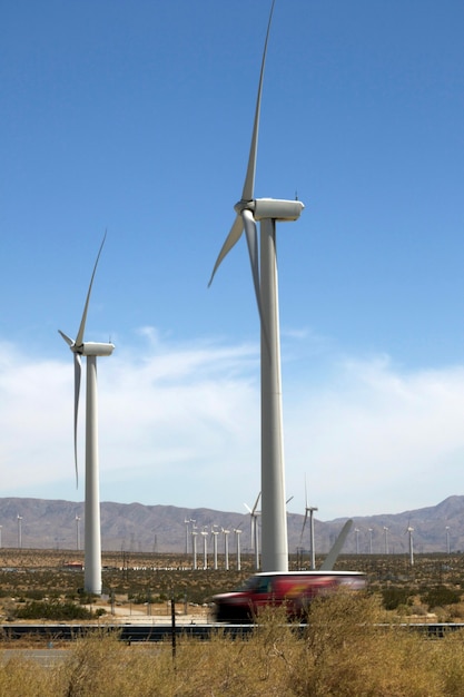 Large windmills in a clear blue sky against the backdrop of mountains and desert Mountain