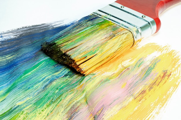 A large wooden art brush paints on canvas.