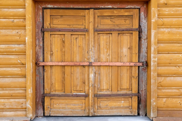 Large wooden gate is closed and metal rusty bolts Preserving the history and architecture of the past Log house