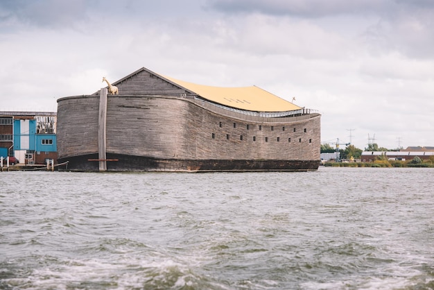 A large wooden ship called noah's ark sits in the water.