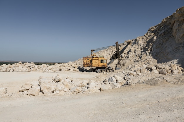 Photo a large yellow tracked excavator is mining rock in a quarry.