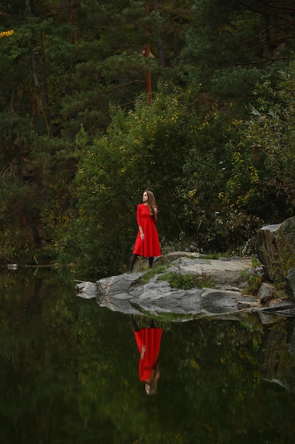 The largest canyon in Ukraine in Korostyshev A girl in a red dress Reflection in water in autumn