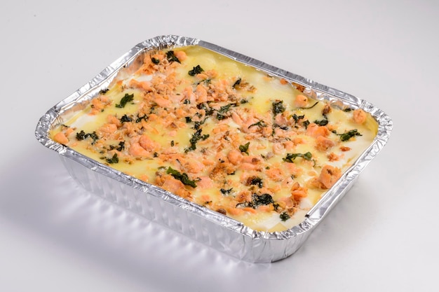 Foto consegna di lasagne lasagne al salmone in confezione per la consegna isolate su sfondo bianco