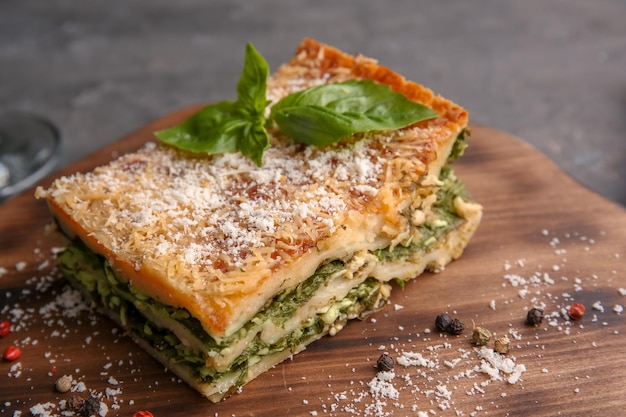 lasagna with spinach on wooden board close up