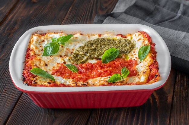 Lasagne gegarneerd met tomatensaus en pesto in bakvorm