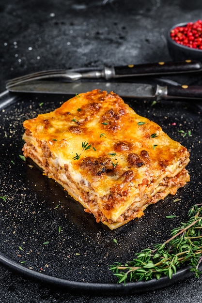 Lasagne met rundergehakt en tomaat bolognesesaus op een bord. Zwarte achtergrond. Bovenaanzicht.