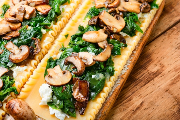 Lasagne with mushrooms,cheese and spinach on wooden table.Traditional Italian food.