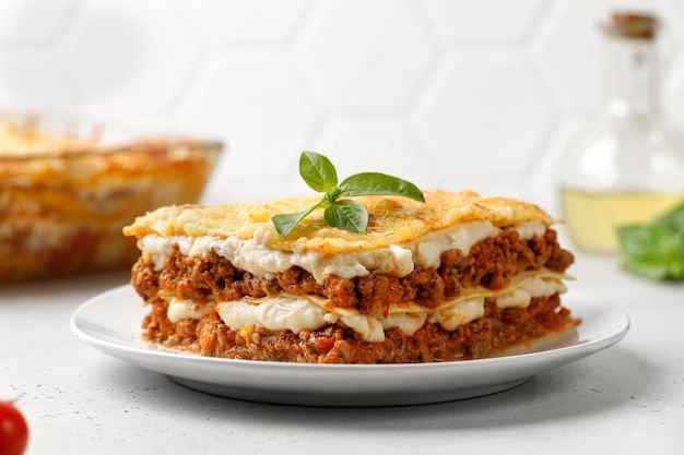 Lasagne zelfgemaakte italiaanse lasagne met bolognese vleessaus, kaas en basilicum op witte plaat