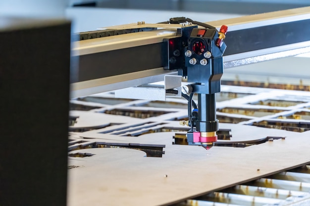 Laser cutting machine cutting wood sheets while a man takes care of the process latin america