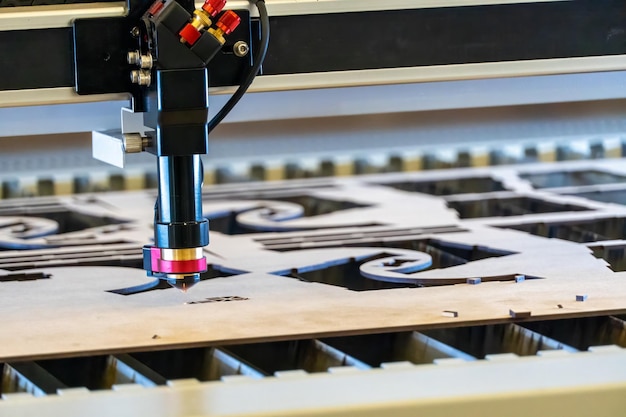 Laser cutting machine cutting wood sheets while a man takes care of the process latin america