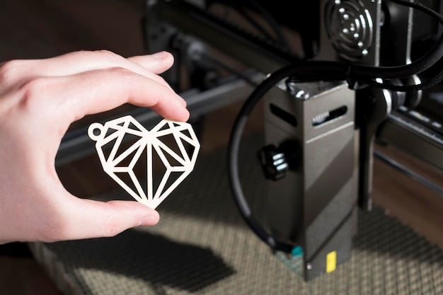 Laser engraving and cutting hand holding an example of a cut out wooden heart