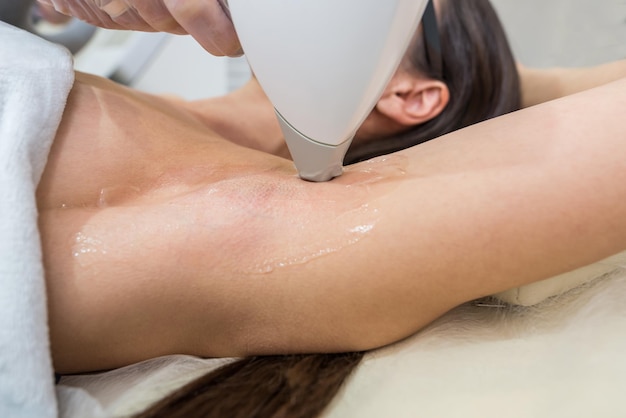 Laser hair removal and cosmetology in a beauty salon hair\
removal procedure the concept of laser hair removal cosmetology spa\
and hair removal beautiful brunette woman getting armpit hair\
removal