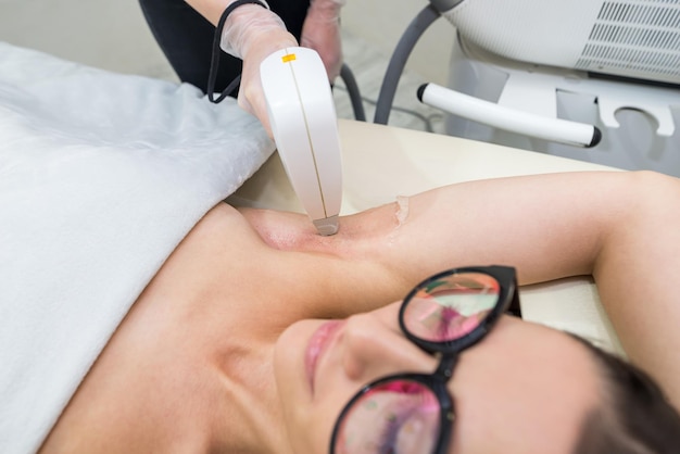 Foto depilazione laser e cosmetologia in un salone di bellezza procedura di depilazione il concetto di depilazione laser cosmetologia spa e depilazione bella donna bruna che ottiene la depilazione delle ascelle