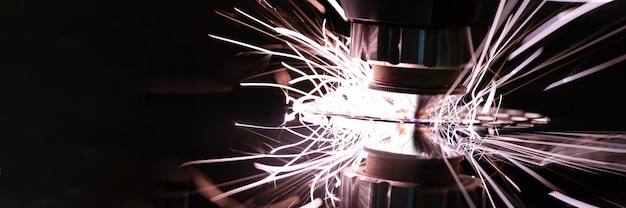 Photo laser machine cutting metal with bright sparks closeup