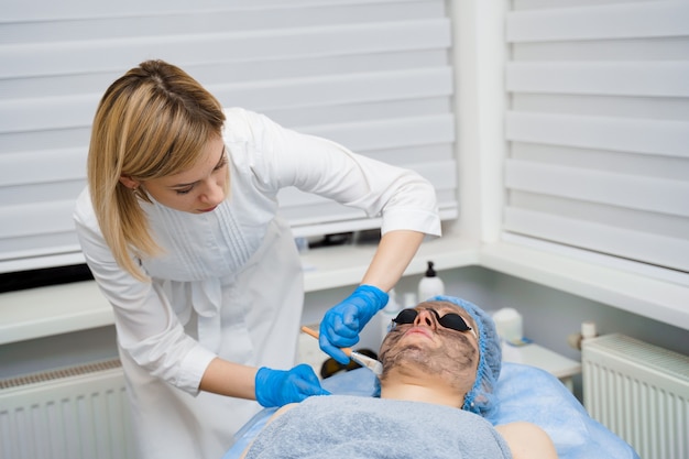 Fotoringiovanimento laser e peeling al carbonio del viso per donna. maschera viso nera. dermatologia e cosmetologia. usando il laser chirurgico.