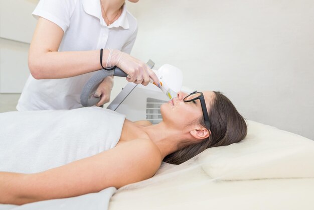 Laser removal hair unwanted on face young woman health and\
beauty concept young woman getting laser hair removal treatment on\
face in salon