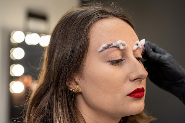 Photo lashmaker applied eyebrow lamination foam to the client's eyebrows