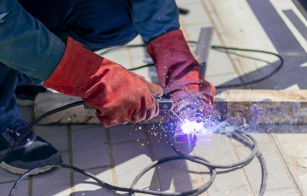 Lasser aan het werk De handen van de lasser dragen beschermende handschoenen die naden maken op metaal