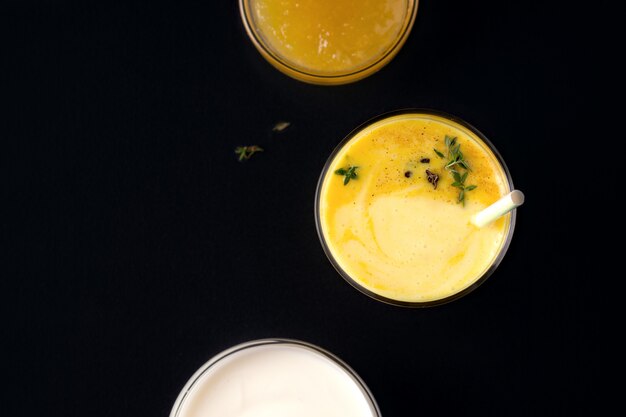 Lassi mangodrank naast jam en yoghurt op zwart