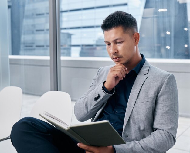 Photo last minute preparation for my interview shot of a young businessman reading a book in a waiting room