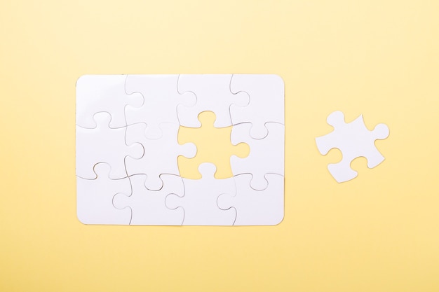 Photo last piece jigsaw white puzzle concept success of business yellow background top view