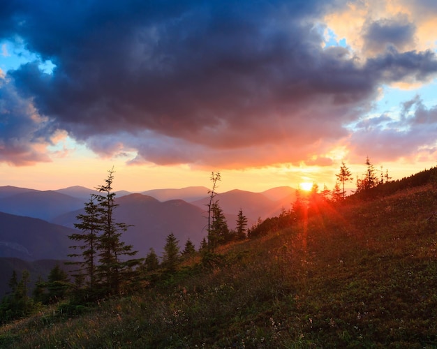 Last rays of setting sun in evening sky with clouds. Summer sunset mountain view (Carpathian, Ukraine).