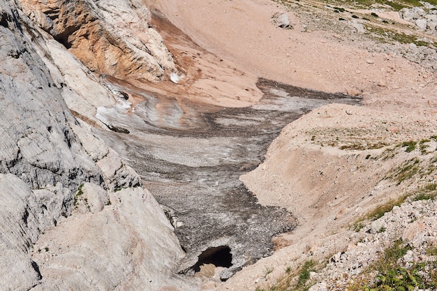 Last remnants of an almost melted glacier at the foot of a cliff in the highlands