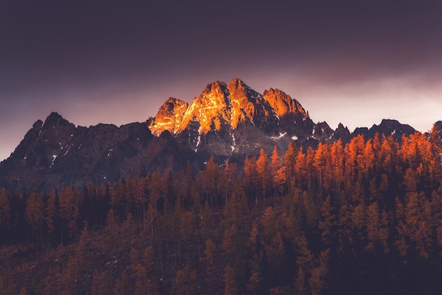 Last sun light hits high mountains peak at sunset