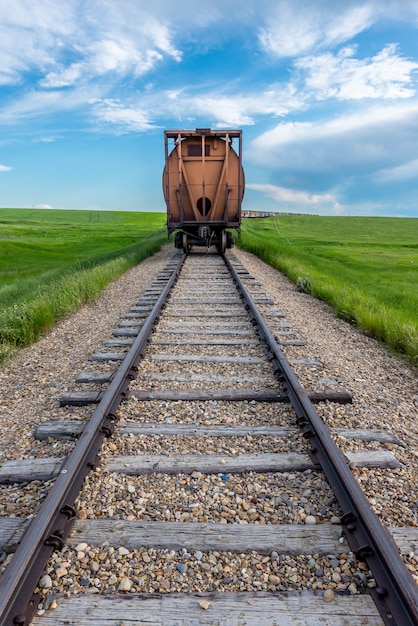 The last train car in a long line with track in the foreground in rural Saskatchewan, Canada
