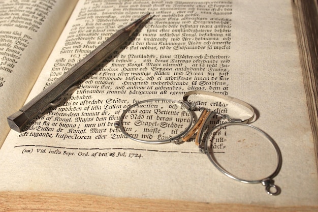 Photo late 19th century scholar's glasses and mechanical pencil are left lying on a 1724 book