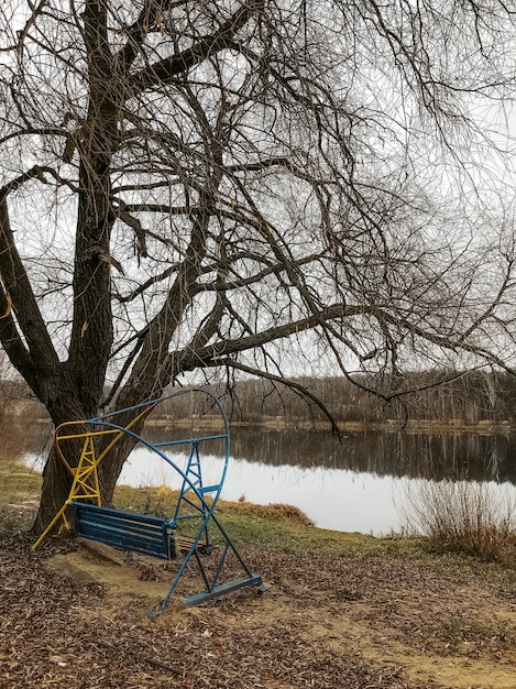 Late autumn landscape with old swings on the lake shore