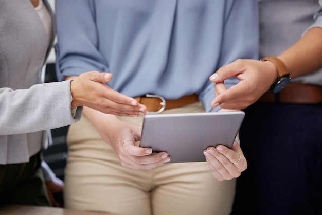 Laten we eens kijken shot van een groep onherkenbare zakenmensen die een digitale tablet gebruiken in een kantoor op het werk