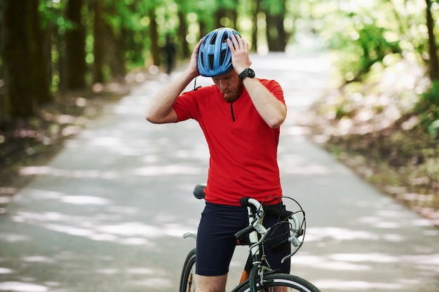 Laten we gaan. Fietser op een fiets is op de asfaltweg in het bos op zonnige dag