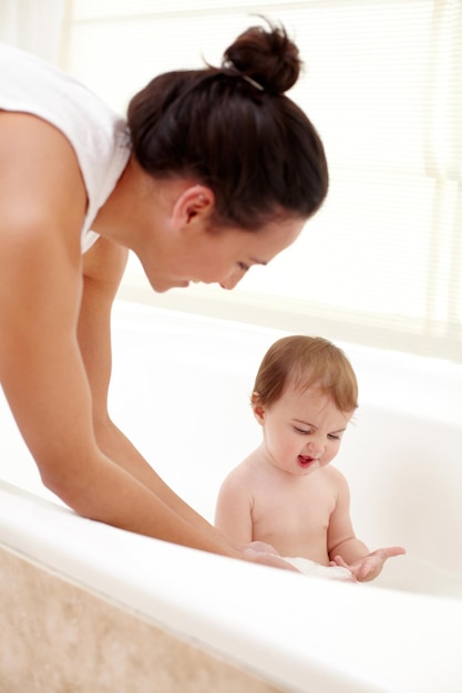 Laten we je schoon en in bed krijgen Een moeder die haar schattige babymeisje in bad wast