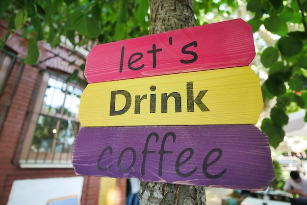 Laten we koffie drinken op een houten bord buiten de koffieshop