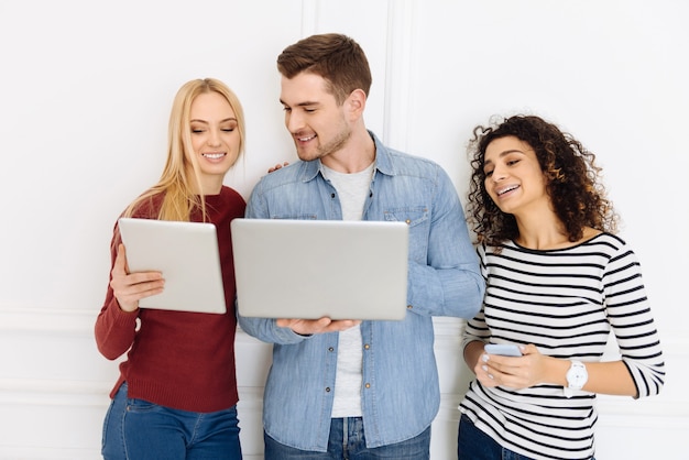 Laten we vergelijken. Vrolijke blonde die positiviteit uitdrukt en in de buurt van haar collega staat terwijl ze haar tablet demonstreert