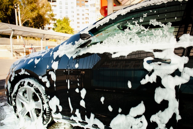 Lateral view beautiful car covered in soap foam